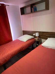 2 Betten in einem rot-weißen Zimmer in der Unterkunft ESCALE BASSIN- Mobile Home Lège Cap-Ferret - Village 4 étoiles LES VIVIERS in Lège-Cap-Ferret + 35 Fotos