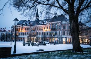 um grande edifício com uma árvore em frente em Varbergs Stadshotell & Asia Spa em Varberg