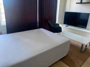 Un dormitorio con una cama blanca y un televisor. en Oslo resident 33L, en Oslo 3 fotos más