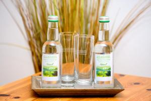 três garrafas e copos numa mesa de madeira em Berghüs Schratt - EINFACH ANDERS - Ihr vegetarisches und veganes Biohotel em Oberstaufen