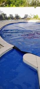 a pool filled with blue water next to chairs at Kooglof Maison in Ostwald