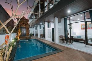 a house with a swimming pool and a bedroom at Langit Guest House Canggu in Canggu