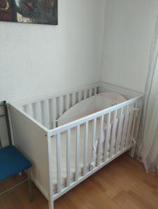 un berceau blanc dans une pièce avec une chaise bleue dans l'établissement Ferienwohnung Lottstetten, à Lottstetten 23 autres photos