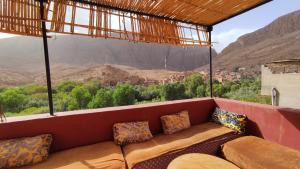 a couch on a balcony with a view of the mountains at La Belle étoile in Aït Oussane