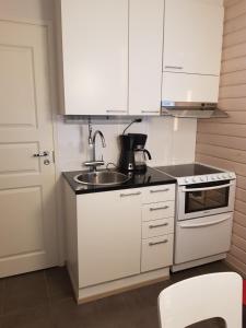 a white kitchen with a sink and a stove at Ranta-Sumpun Helmi 10 Beach house with sauna in Hailuoto