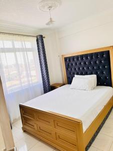 una camera da letto con un letto grande con testiera blu di Residence Next Door Green Zone a Kiambu