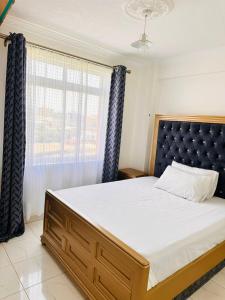 una camera da letto con un letto grande e una finestra di Residence Next Door Green Zone a Kiambu