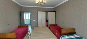 a room with two beds and a table in it at Qonaq evi quest home in Sheki