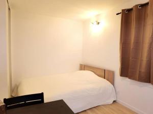 a small bedroom with a white bed and a table at New renoveted studio in calm area near nation in Paris