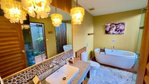 a bathroom with a tub and a toilet and a sink at Deva Beach Resort Samui in Choeng Mon Beach