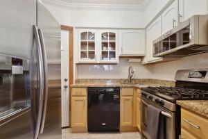 Una cocina con gabinetes blancos y un refrigerador de acero inoxidable. en In the heart of historic Fells Point!!!, en Fells Point