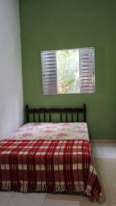 a green bedroom with a bed with a plaid blanket at Recanto massaguaçu in Massaguassu