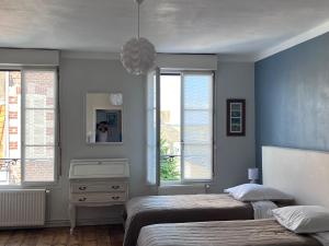 a bedroom with two beds and two windows at Maison de vacances les Coulonneux in Saint-Valery-sur-Somme