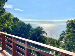 a view of the ocean from a wooden balcony at Double Deck - Linda vista para ilha de Floripa com Jacuzzi in Palhoça