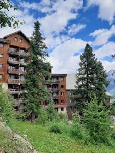 a tall building with two trees in front of it at T2 proche pistes & promo forfaits in Puy-Saint-Vincent