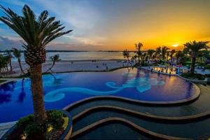 a resort pool with a palm tree and a sunset at Full Sea View Country Garden Danga Bay 6-13pax Smart TV 70inch-Netflix in Johor Bahru