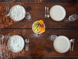 a wooden table with plates and utensils and a bowl of fruit at Ananya Apartments Phase 1 in Kathmandu