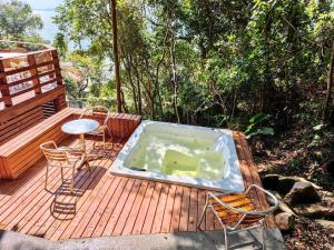 a hot tub on a deck with a table and chairs at Double Deck - Linda vista para ilha de Floripa com Jacuzzi in Palhoça