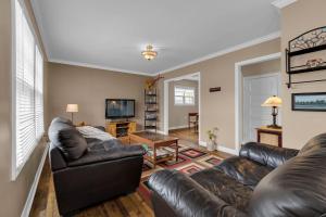 Una sala de estar con un sofá de cuero y un televisor. en Cottage Feel in the City Close to Everything, en Saint John