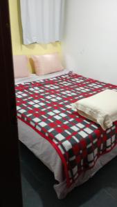 a bed with a checkered blanket on top of it at Casa Calhetas Pousada I in São Sebastião +3 photos