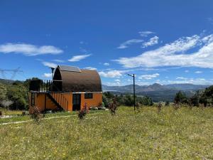 a barn on a hill with a field of flowers at Glamping Terranova Guatavita Colombia in Guasca