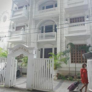 エルナクラムにあるBanyan Tree Homestayの白い建物の前を歩く女