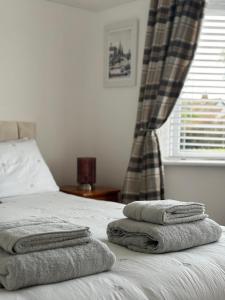 a bed with three towels sitting on top of it at Victoria Beach Cottage in Prestatyn