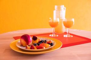 a plate of fruit on a table with two glasses of juice at Yellow House - Lugano in Lugano