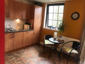 a kitchen with a table and chairs and a clock on the wall at The Pentland Apartment in Penicuik