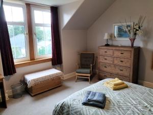 a bedroom with a bed and a dresser and a chair at Esk Cottage in Pitlochry