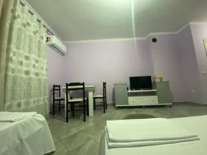 ポグラデツにあるGenti Guesthouseのテーブルと椅子とテレビのある部屋