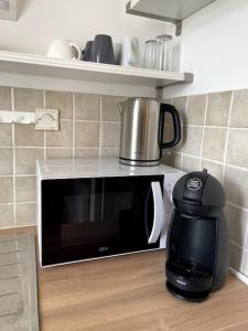 a microwave oven with a coffee pot on top of it at Modern Art Vierzon Centre ville in Vierzon