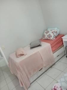 a bed with a table with a pink blanket on it at Apartamento Praia das Pitangueiras - Condomínio Golden Tower in Guarujá
