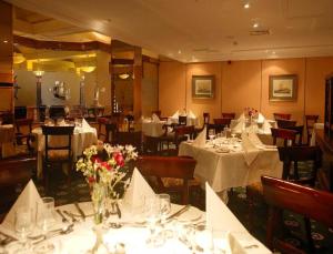 um restaurante com mesas com toalhas de mesa brancas e flores em Brandon Hotel Conference & Leisure Centre em Tralee