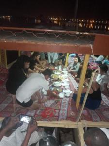 a group of people sitting around a table eating food at Relaxing Felucca Trips in Aswan +17 photos