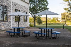two tables and two umbrellas in front of a building at Holiday Inn Express - Grand Island by IHG in Niagara Falls