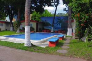 a pool with a slide and two benches next to trees at Rincon del mar in La Libertad