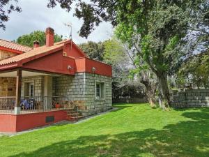 a house with a green yard next to a tree at Casa rural chimenea y barbacoa in Escorial