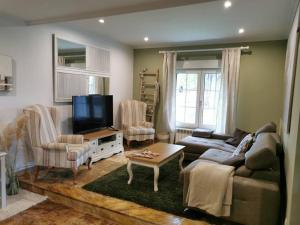 a living room with a couch and a flat screen tv at Casa rural chimenea y barbacoa in Escorial