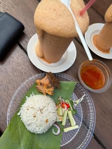 a table with a plate of rice and a drink at Eyka Studio Roomstay in Marang