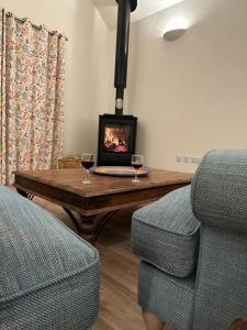 a living room with a fireplace and a table with two glasses of wine at The Saddlehouse at Wykeham in Biscathorpe