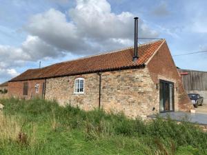 an old brick building in a field of grass at The Saddlehouse at Wykeham in Biscathorpe