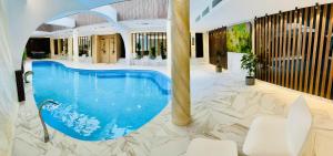 a large swimming pool in a lobby with white chairs at Eurohotel in Baia Mare