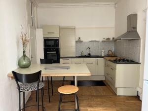 kuchnia ze stołem i krzesłami oraz kuchnia z białymi szafkami w obiekcie La Villa Louana 1 Appartement 160m2 sobriété,élégance en cœur de ville w mieście Aubusson