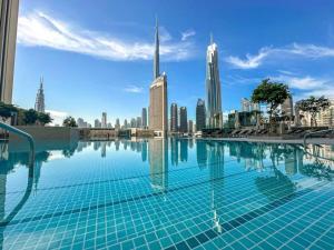 een zwembad met een skyline van de stad op de achtergrond bij LUXE | 2BR | Burj Khalifa View | Dubai Mall Access in Dubai