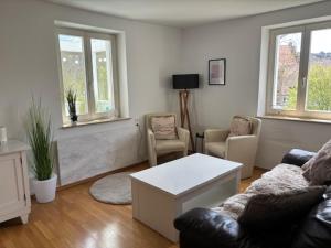 a living room with a couch and chairs and windows at Haus Theresia in Zwiefalten