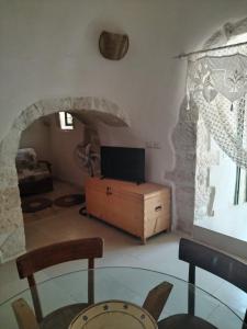a living room with a glass table and a tv at Trullo Amedee in Ostuni +35 photos