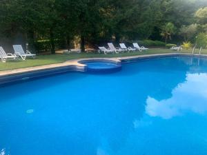 a large blue swimming pool with chairs and trees at Moradia 3 quartos com piscina partilhada no Gerês Caniçada Braga in Vieira do Minho