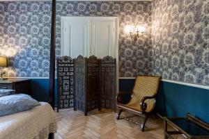 a bedroom with a bed and a chair and a mirror at La casa di K i p l i n g "charme coloniale & storia" in Gorizia +34 photos