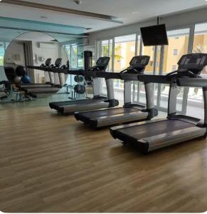 a gym with rows of treadmills and mirrors at ILHA DA MADEIRA Resort apto inteiro in Riviera de São Lourenço